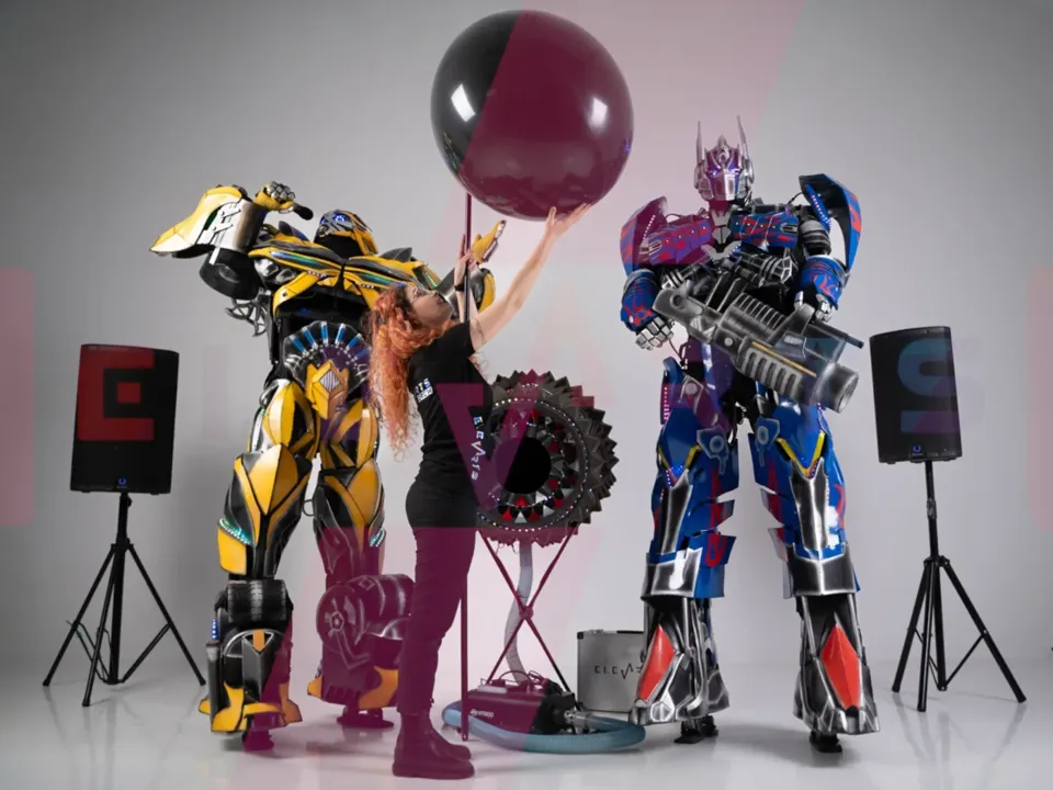 Optimus Prime și Bumblebee lângă balonul jumbo, cu MC-ul în față